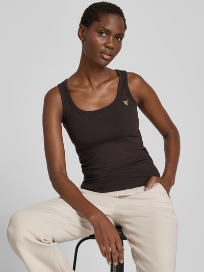 Kobiece model prezentuje top Tanktop in Ripp-Optik mit Label-Applikation Model 'COLETTE' od GUESS, mieszanka wiskozy i elastanu, krój slim fit, efekt prążkowania, aplikacja z metką, Długość tyłu w rozmiarze S: 50 cm, kolory czarny i beżowy, tekstura prążkowana, prosty fason, neutralne tło, zbliżenie na górną część ciała, ujęcie z przodu