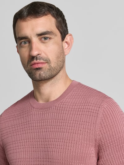 Männermodel trägt Strickshirt mit Strukturmuster Modell 'Elio' von JOOP! COLLECTION in Rosa, Rundhalsausschnitt, Nahaufnahme Oberkörper.