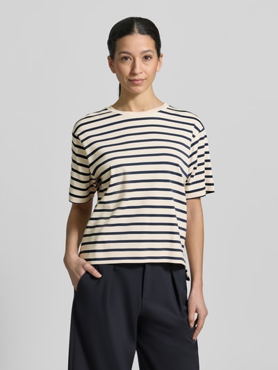 Modelka nosi Regular Fit T-Shirt aus reiner Baumwolle Modell 'MULTID' od Weekend Max Mara, krój regular fit, jednolity wzór z logo, okrągły dekolt, krótkie rękawy, asymetryczny dół z rozcięciem po bokach, materiał w drobny prążek, kolor kremowy z granatowymi pasami, widok na całą sylwetkę z przodu.