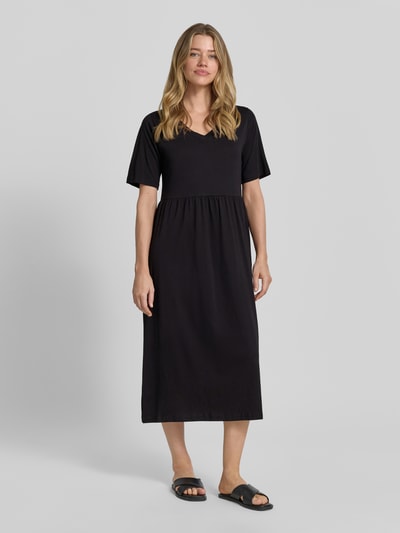 Frauenmodel trägt Midikleid mit Smok-Details Modell 'DERBY' von Soyaconcept in Schwarz, A-Linie, Reine Baumwolle, Ganzkörperansicht von vorne. Rückenlänge 117 cm, Brustweite 44 cm, Ärmellänge 27 cm, Rundhalsausschnitt.