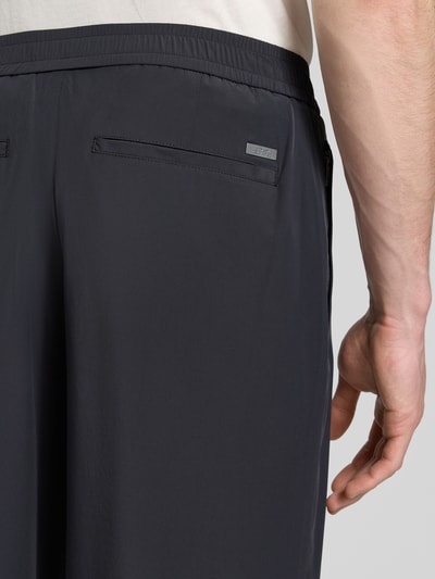 Mężczyzna nosi Hose mit elastischem Bund und Gesäßtaschen von ARMANI EXCHANGE, materiał z domieszką stretchu, krój relaxed fit, kolor ciemnoszary, tylne kieszenie, Szerokość w rozmiarze 32: 40 cm, długość nogawki od wewnątrz 79 cm, zbliżenie tylnej części spodni.