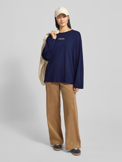 Frauenmodel trägt Oversized Langarmshirt aus reiner Bio-Baumwolle Modell 'FIETAA DIFFERENCE' von Armedangels in Unifarben, Statement-Print, Label-Print, überschnittene Schultern, Rundhals, Ärmelform langarm, Jersey-Material, Ganzkörperansicht von vorne.