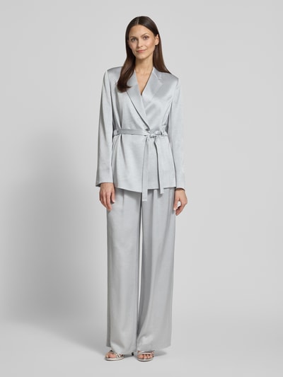 Kobiece modelka nosi Wide Fit Stoffhose mit gelegten Falten von Marc Cain, mieszanka acetatu, wpuszczane i tylne kieszenie, zapięcie na haftkę i zamek błyskawiczny, szerokość w rozmiarze 36: 38 cm, długość wewnętrzna nogawki w rozmiarze 36: 83 cm, widok całej sylwetki z przodu.