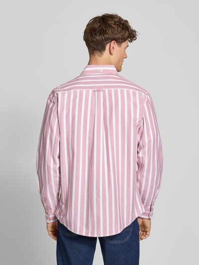 Mężczyznamodel nosi koszulę casualową Regular Fit Freizeithemd mit Logo-Stitching Modell 'Deven' od Carhartt Work In Progress, w białe i różowe pionowe paski, z długim rękawem, z czystej bawełny, kołnierzyk typu button down, sportowe mankiety, widoczne wyhaftowane logo, długość tyłu w rozmiarze M 77 cm, szerokość w rozmiarze M 48 cm, długość rękawów w rozmiarze M 65 cm, widok całej sylwetki z tyłu.