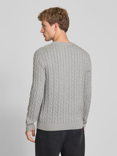 Männermodel trägt grauen Slim Fit Strickpullover reine Baumwolle von REVIEW mit Zopfmuster, Logo Stickerei, gerippten Bündchen, Ganzkörperansicht Rückansicht.