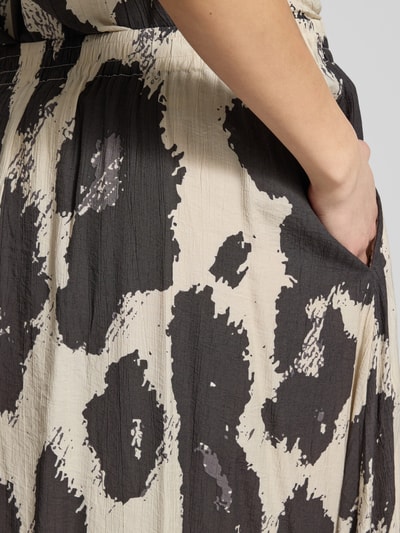 Frauenmodel trägt Midirock aus Viskose-Mix Modell 'Karalie' von MSCH Copenhagen, grafisches Schwarz-Beige-Muster, elastischer Bund, Eingrifftaschen, A-Linie, Nahaufnahme Oberkörper.
