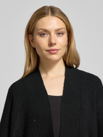 Frauenmodel trägt Poncho mit 1/2-Ärmel Modell 'Ablanki' von Opus, schwarze Farbe, gerippte Abschlüsse, Nahaufnahme Oberkörper.