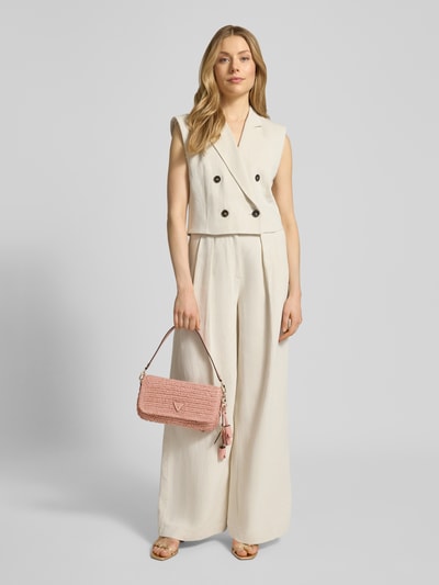 Modelka kobieca nosi Shoulder Bag in Flecht-Optik Modell 'OFELIA' od Guess, efekt plecionki, detal z logo, zapięcie na magnes, odpinany pasek na ramię, główna przegroda z klapką, wewnętrzna kieszeń zapinana na zamek błyskawiczny, szerokość w rozmiarze 1: 28 cm, długość w rozmiarze 1: 16 cm, głębokość w rozmiarze 1: 6 cm, długość paska na ramię w rozmiarze 1: 130 cm, widok całej sylwetki z przodu.