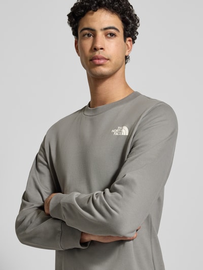 Männermodel trägt Sweatshirt mit Label-Print van The North Face, katoen, grijs, geribde boorden, ronde hals, labelprint, Nahaufnahme Oberkörper.