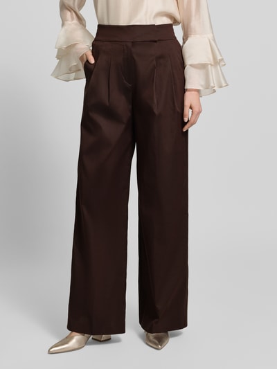 Modelka nosi spodnie materiałowe 'Stoffhose mit französischen Eingrifftaschen' od Windsor, mieszanka bawełny z dodatkiem streczu, krój wide leg, zapięcie na haftkę, guzik i zamek błyskawiczny, wpuszczane kieszenie francuskie, kieszenie z wypustką z tyłu, szerokość w rozmiarze 36: 36 cm, długość wewnętrzna nogawki w rozmiarze 36: 82 cm, ciemny brąz, gładka tekstura, widok całej sylwetki z przodu.