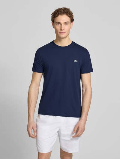 Männermodel trägt Regular Fit T-Shirt aus Baumwoll-Mix von Lacoste Sport, unifarben, Logo-Patch, Rundhals, kurzarm, Ganzkörperansicht von vorne.