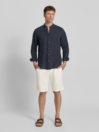Männermodel trägt Tapered Chinoshorts aus Leinen-Mix Modell 'DS_3S' von BOSS Orange in Creme mit Label-Patch und Flammgarn-Struktur, Ganzkörperansicht von vorne.
