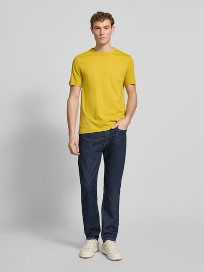 Männermodel trägt Regular Fit T-Shirt aus reiner Baumwolle Modell 'TEGOOD' von BOSS Orange in Gelb, unifarben, Ganzkörperansicht von vorne.