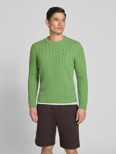Männermodel trägt Regular Fit Strickpullover aus Baumwoll-Mix von Lacoste, Optik: Unifarben, Zopfmuster, Nahaufnahme Oberkörper.