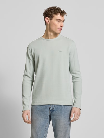 Männermodel trägt Regular Fit Langarmshirt aus Baumwoll-Mix Modell 'TEMPESTO' von BOSS Orange in hellem Uni, Waffel-Optik, Ganzkörperansicht von vorne.