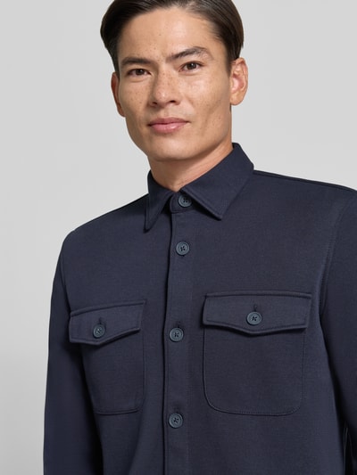 Männermodel trägt Overshirt mit Knopfleiste von MCNEAL in Dunkelblau, glatte Textur, Brusttaschen, Material-Mix mit Baumwoll-Anteil, Nahaufnahme Oberkörper.