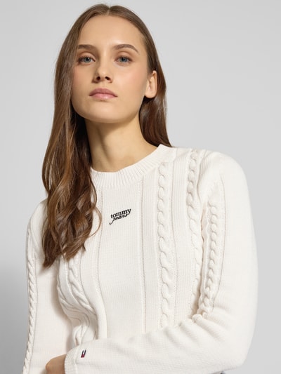 Frauenmodel trägt Slim Fit Strickpullover aus reiner Baumwolle von Tommy Jeans in Optik: Unifarben, Strickoptik, Nahaufnahme Oberkörper.