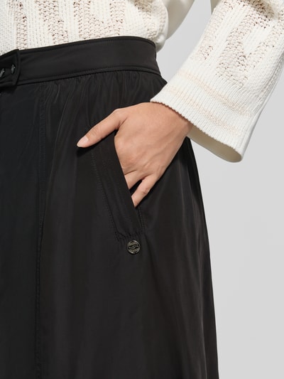 Frauenmodel trägt Midirock mit Eingrifftaschen von Marc Cain in Schwarz, A-Linie, Teilungsnähte, Detailaufnahme, Kontext: Damen Midirock von Marc Cain, Knopf- und Reißverschluss, Bundweite 37 cm, Länge 87 cm.