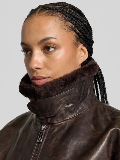 Frauenmodel trägt Lederjacke mit Umlegekragen von Victoria Beckham aus echtem Leder, dunkelbraun, sichtbare Reißverschluss-Details, Nahaufnahme Oberkörper.