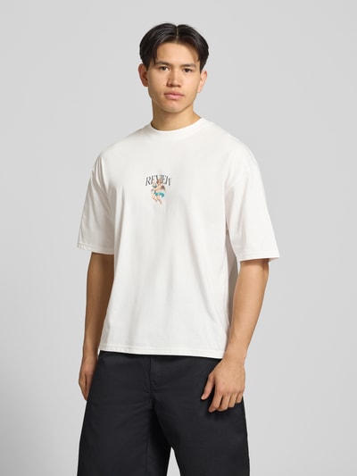 Männermodel trägt T-Shirt mit überschnittenen Schultern von REVIEW, Herren T-Shirt aus Reine Baumwolle, Lockerer-Schnitt, Weiß, Label-Print, Rundhalsausschnitt, Rückenlänge 70 cm, Ganzkörperansicht von vorne.