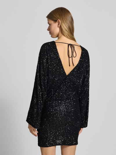Frauenmodel trägt Minikleid mit Rundhalsausschnitt von Gina Tricot in Schwarz mit Paillettenbesatz, taillierter Schnitt, Material-Mix mit Stretch-Anteil, Unterkleid, Rückenlänge 86 cm, Ärmellänge 63 cm, Ganzkörperansicht Rückansicht.