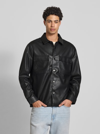 Mannenmodel draagt Regular Fit Hemdjacke in leerlook van Calvin Klein Jeans, zwart, platte kraag, borstzakken, knoopsluiting, sportmanchet. Ganzlichaamsaanzicht van voren. Context: Heren Hemdjacke van Calvin Klein Jeans, leerlook, regular fit, platte kraag, borstzakken, knoopsluiting, sportmanchet, ruglengte bij maat M: 73 cm, schouderbreedte bij maat M: 50 cm, mouwlengte bij maat M: 65 cm.