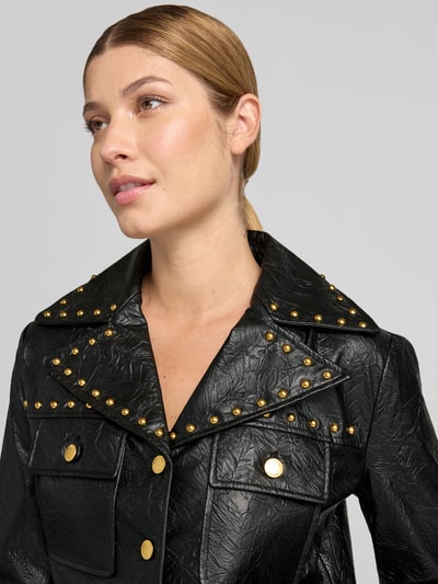Frauenmodel trägt Cropped Jacke in Leder-Optik Modell 'STUDDED' von MICHAEL Michael Kors mit Nieten und Reverskragen, Nahaufnahme Oberkörper.