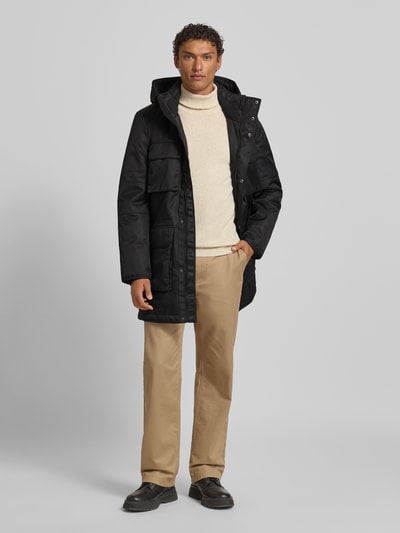 Männermodel trägt Jacke mit Pattentaschen Modell von NAUTGÅRD in Schwarz, Regular-Fit, Kapuze, glatte Textur, Ganzkörperansicht von vorne. Rückenlänge bei Größe M 96 cm, Schulterbreite 46 cm, Brustweite 59 cm, Ärmellänge 71 cm.