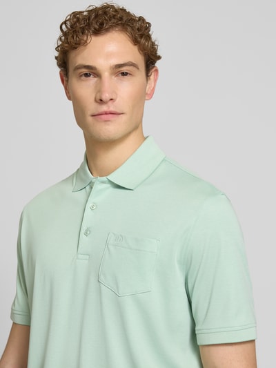 Männermodel trägt Regular Fit Poloshirt mit Brusttasche und Label-Stitching von bugatti in Mintgrün, Nahaufnahme Oberkörper.