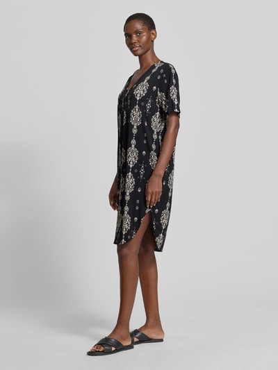 Frauenmodel trägt knielanges Kleid mit V-Ausschnitt Modell 'Floy' von FREE/QUENT, schwarz mit cremefarbenem Muster, gerader Schnitt, Material-Mix mit Stretch-Anteil, Ganzkörperansicht von vorne.