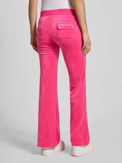 Kobiece model nosi Low Rise Sweatpants mit elastischem Bund Model 'LAYLA' von Juicy Couture z mieszanki bawełny, rozkloszowany krój, niski stan, wpuszczane kieszenie, kolor różowy, długość wewnętrzna nogawki 39 cm dla rozmiaru S, widok całej sylwetki z tyłu.