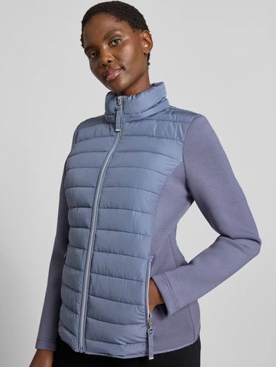 Vrouwenmodel draagt Steppjacke mit Kapuze und Reißverschlusstaschen van Christian Berg Woman Selection in regular fit, lichtblauw met glanzende textuur, rits en zakken, materiaal- en maatinformatie uit context, nahaufnahme bovenlichaam.