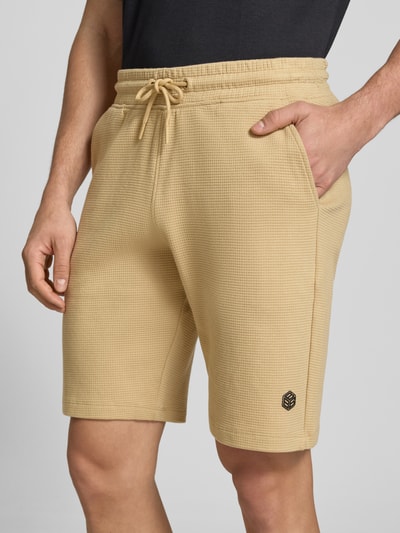 Mannenmodel draagt Straight Fit korte broek met logostitching model 'Fillip' van Blend, puur katoen, structuurpatroon, steekzakken, elastische band met tunnelkoord, beige; close-up bovenlichaam vooraanzicht.