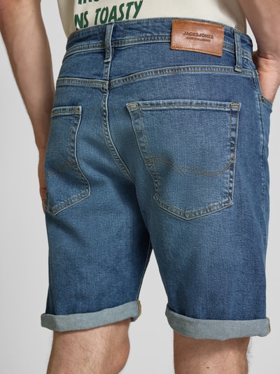 Männermodel trägt Regular Fit Jeansshorts mit Umschlag Modell 'RICK' von Jack & Jones aus Baumwoll-Elasthan-Mix, Eingrifftaschen, Rückansicht Ganzkörperansicht.