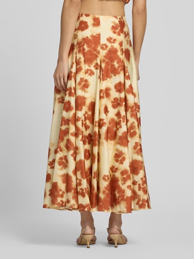 Vrouwenmodel draagt Maxirok uit viscosemix met bloemen all-over print van Jake*s Cocktail, A-lijn, stolpplooien, bandwijdte maat 36: 34 cm, totale lengte maat 36: 90 cm, geheel in warme bruine en beige tinten. Ganzkörperansicht Rückansicht.