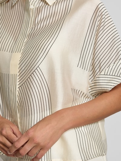 Vrouwenmodel draagt Boxy Fit Bluse aus Lyocell-Mix Modell 'Zulin' van Someday met overhemdkraag, verborgen knoopsluiting, crèmekleurige stof met zwarte lijnen, lyocellmix, detailopname bovenlichaam.