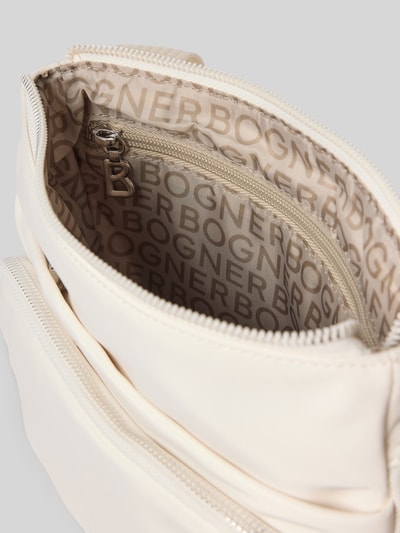 Produktfoto, cremefarbene Handtasche mit Label-Detail Modell 'verbier play 1.0 serena' von BOGNER, Hauptfach mit Reißverschluss, Innenfutter mit BOGNER-Print, verstellbarer Schulterriemen, Breite 25 cm, Länge 25 cm, Tiefe 4 cm, Länge Schulterriemen 105 cm.