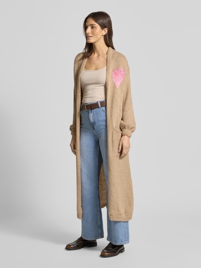 Frauenmodel trägt Longcardigan mit Eingrifftaschen von miss goodlife aus Baumwoll-Alpaka-Mix, beige, lockerer Schnitt, gerippte Abschlüsse, Ganzkörperansicht von vorne.