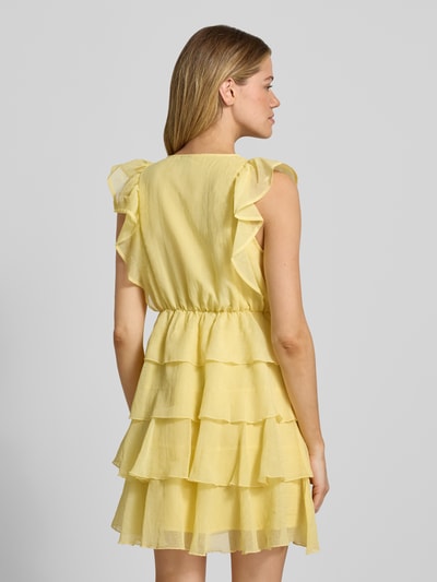 Frauenmodel trägt Tailliertes Cocktailkleid mit Wickeloptik Modell 'SABRINA' von Vero Moda aus gelbem Chiffon, Volants, Mini-Länge, tiefem V-Ausschnitt, Ganzkörperansicht Rückansicht