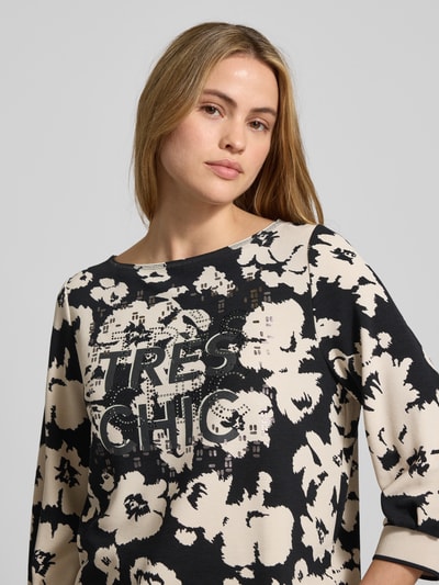 Frauenmodel trägt Sweatshirt aus Viskose-Mix mit 3/4-Arm von Betty Barclay, beige-schwarzer Allover-Look, Statement-Print, Nahaufnahme Oberkörper.