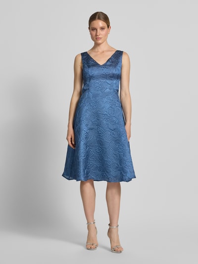 Frauenmodel trägt Cocktailkleid mit Strukturmuster und V-Ausschnitt von Vera Mont in A-Linie als Midikleid, blauer Ton, Ganzkörperansicht von vorne. Rückenlänge bei Größe 36: 103 cm, Brustweite bei Größe 36: 44 cm.