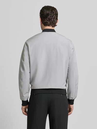 Männermodel trägt Regular Fit Bomberjacke mit Stehkragen von MCNEAL in Hellgrau mit elastischen Abschlüssen, glatte Textur, Ganzkörperansicht Rückansicht.