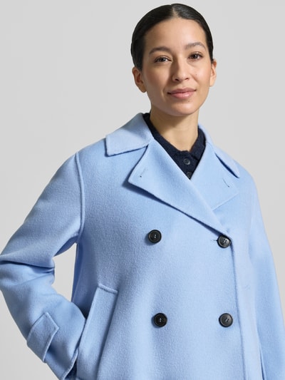 Männermodel trägt Loose Fit Wollmantel aus Schurwoll-Mix Modell 'FANTINO' von Weekend Max Mara, jasny niebieski, dwurzędowy, krój loose fit, wełna dziewicza, kieszenie z boku, gładka faktura, zamszowy kołnierz, całkowite ujęcie górnej części ciała z przodu.