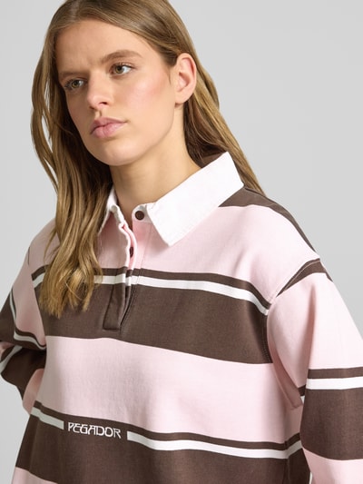 Frauenmodel trägt Pegador Sweatshirt mit Polokragen Modell 'MORELLA', Reine Baumwolle, Loose-Fit, Logo-Print, rosa und braun, Nahaufnahme Oberkörper.