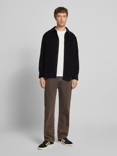 Männermodel trägt Relaxed Fit Freizeithemd in Cord-Optik Modell 'Roy' von Calvin Klein Jeans in Schwarz mit Brusttaschen, Ganzkörperansicht von vorne.