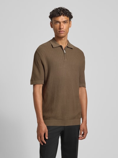 Männermodel trägt Regular Fit Poloshirt aus reiner Bio-Baumwolle Modell 'CRAN' von SELECTED HOMME in Strickoptik mit Struktur-Muster, Polokragen, V-Ausschnitt und kurzem Reißverschluss, Farbe Braun, Kurzarm, gerippte Abschlüsse, Ganzkörperansicht von vorne.