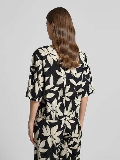 Frauenmodel trägt Relaxed Fit Blusentop aus Viskose-Mix von s.Oliver RED LABEL mit floralem Allover-Muster in Schwarz und Creme, Rückansicht.