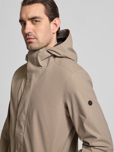 Męski model trägt Parka mit Ärmelriegeln Modell 'GEORGE' von Didriksons, krój regular fit, kaptur, nahaufnahme oberkörper, kolor beżowy, kontekst: długość tyłu w rozmiarze M 94 cm, szerokość ramion w rozmiarze M 45 cm, szerokość klatki piersiowej w rozmiarze M 55 cm, długość rękawów w rozmiarze M 67 cm.