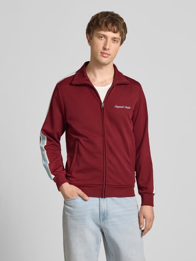 Männermodel trägt Sweatjacke mit Stehkragen Modell 'COTEDAZUR' von Jack & Jones, Slim Fit, bordeaux, Reißverschluss, Nahaufnahme Oberkörper.