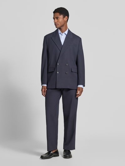 Männermodel trägt dunkelblaue Loose Fit Anzughose mit Gürtelschlaufen Modell 'LOOSE-LIAM' von Selected, Ganzkörperansicht von vorne.